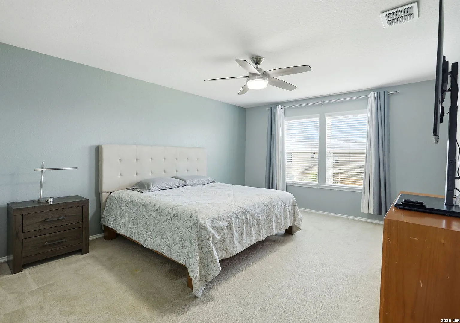 Primary bedroom with carpet, windows with natural light, and a ceiling fan.