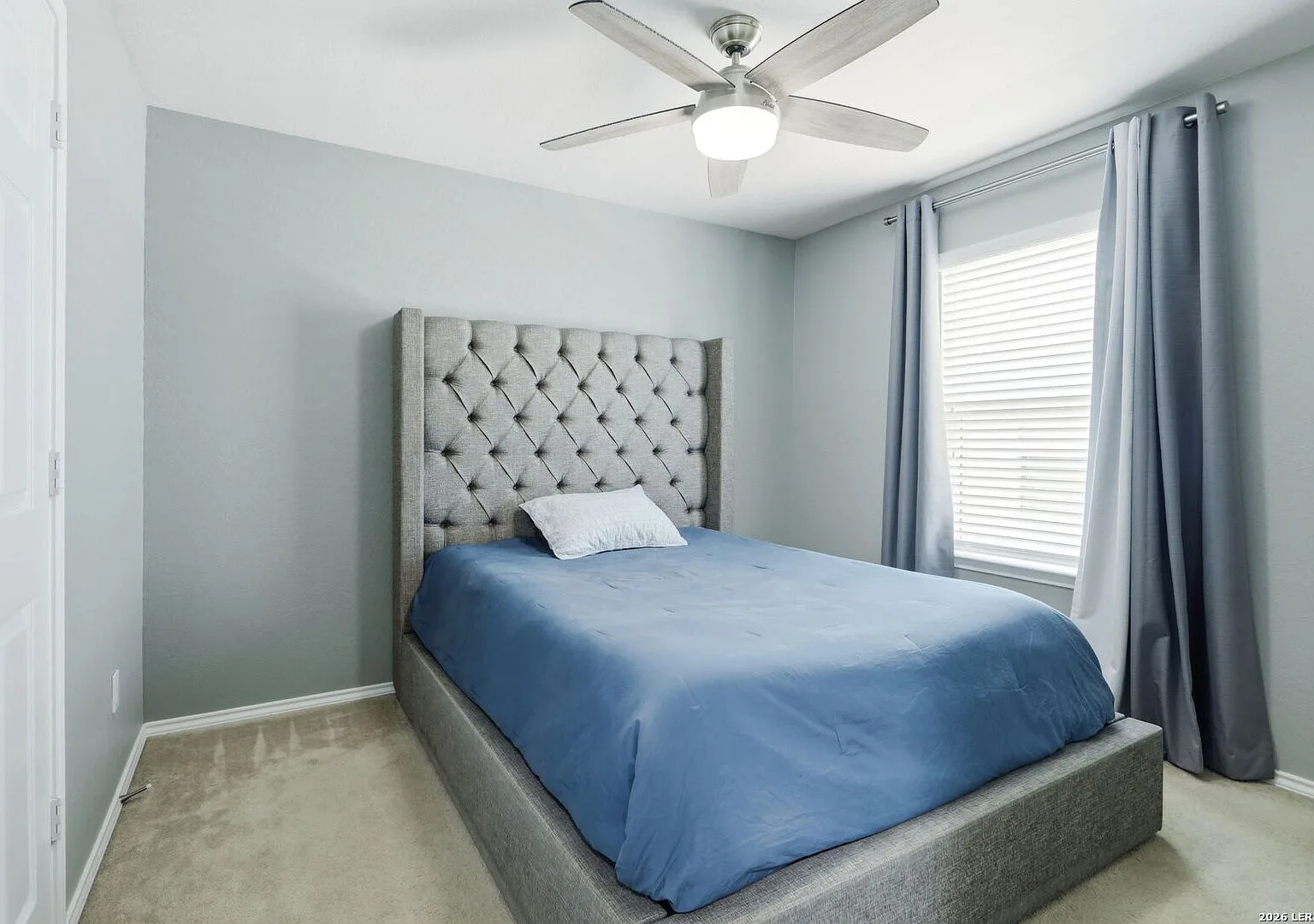 Secondary bedroom with neutral grey walls and natural light from a window.
