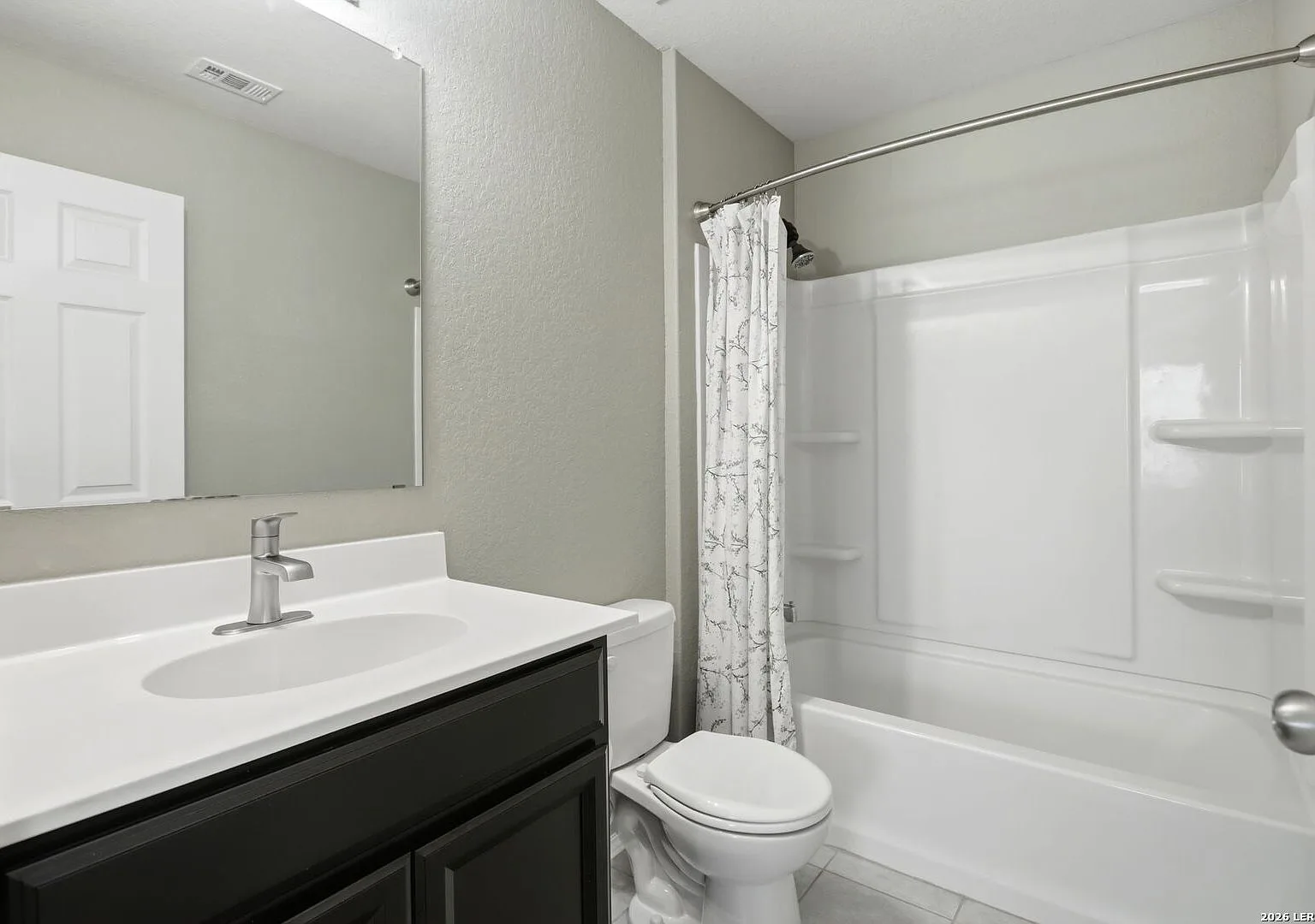 Secondary bath with a white tub-shower combo and dark vanity cabinet.