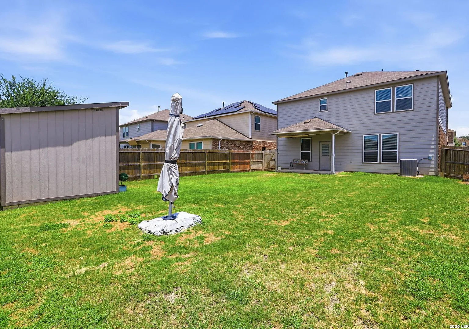 Rear exterior of the two-story home with a covered patio and storage shed.