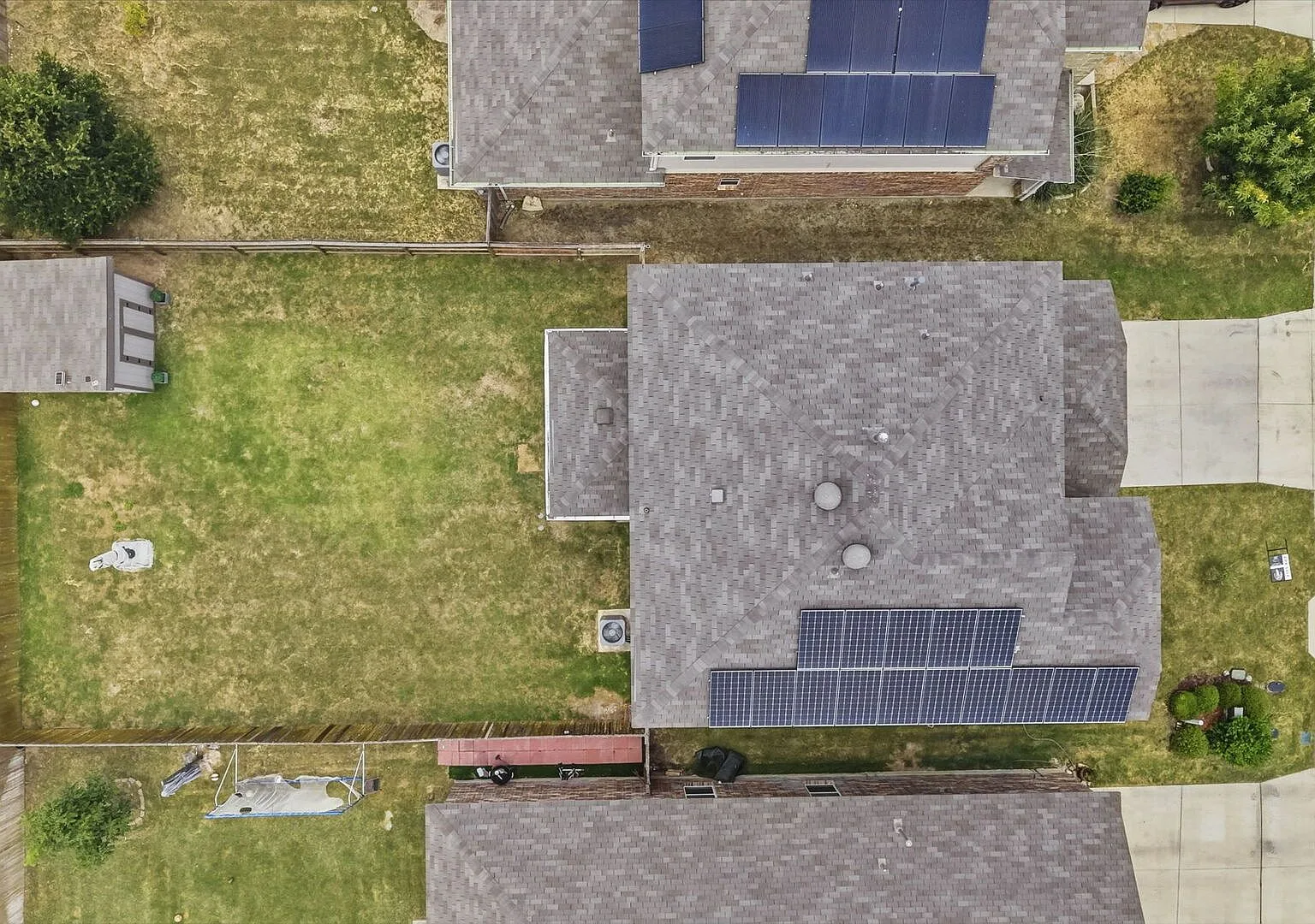 Aerial view of the home showing roof-mounted solar panels and the backyard.