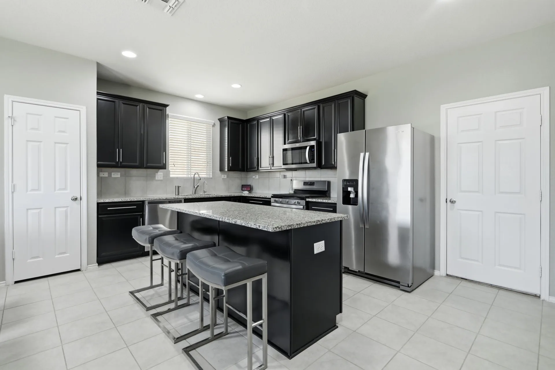 Kitchen with black cabinetry, granite countertops, and stainless steel appliances.