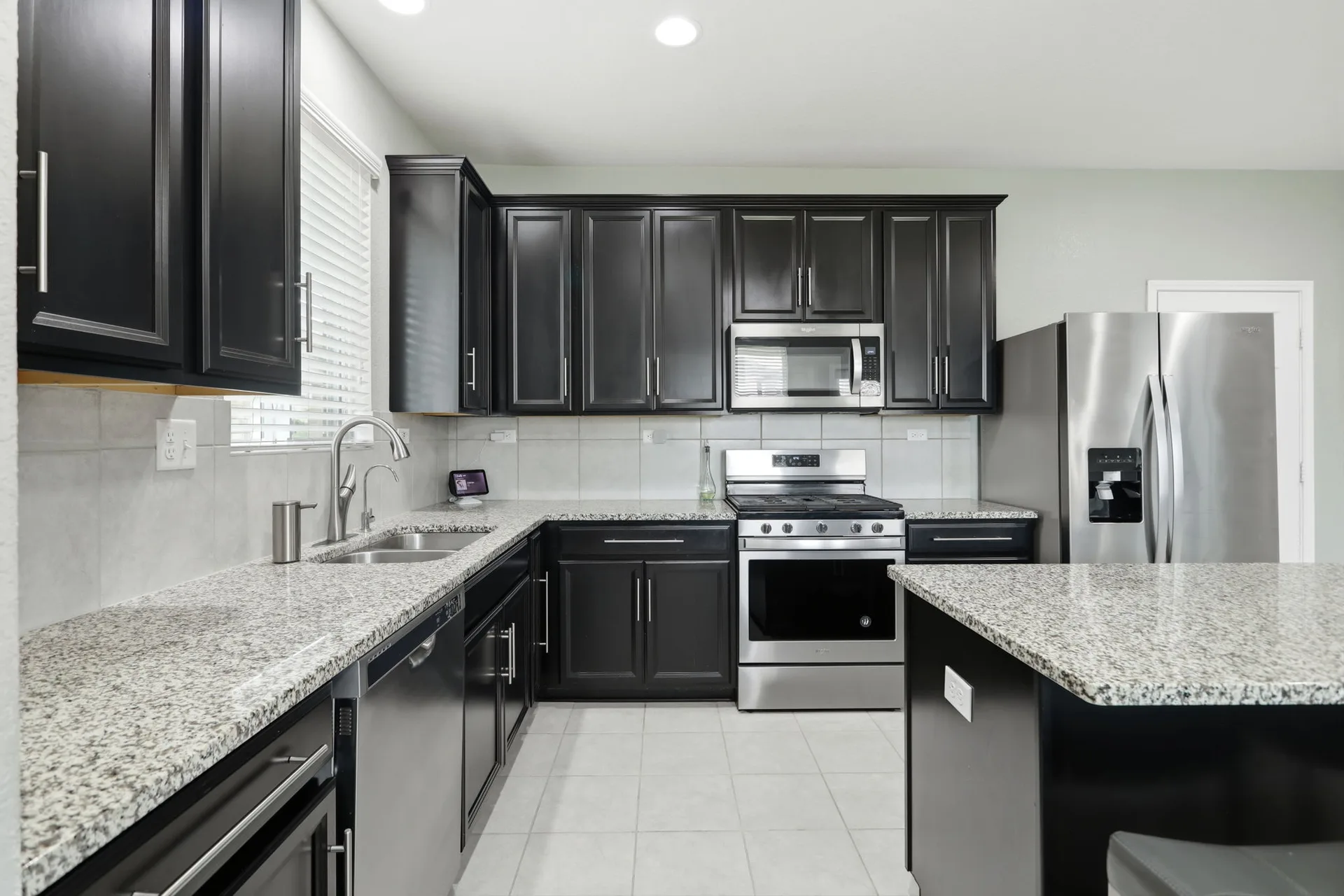 Kitchen with dark espresso cabinetry and speckled granite countertops.