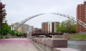 Riverside walkway and pedestrian bridge near downtown Sioux Falls with apartment buildings behind