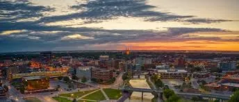 Aerial view of the Sioux Falls skyline at sunset with the Big Sioux River and a bridge below