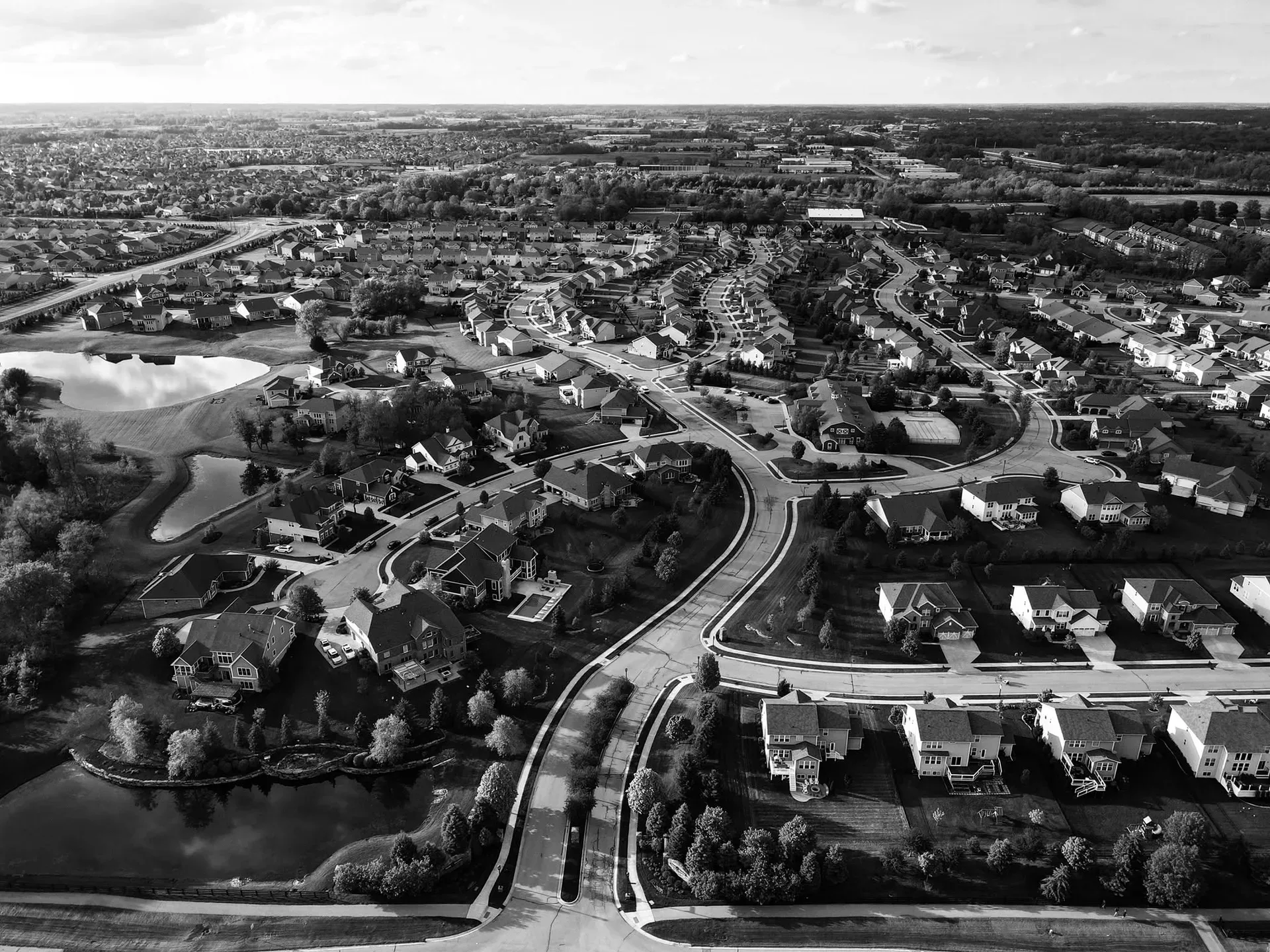 An aerial view of a suburban neighborhood of single-family homes with retention ponds