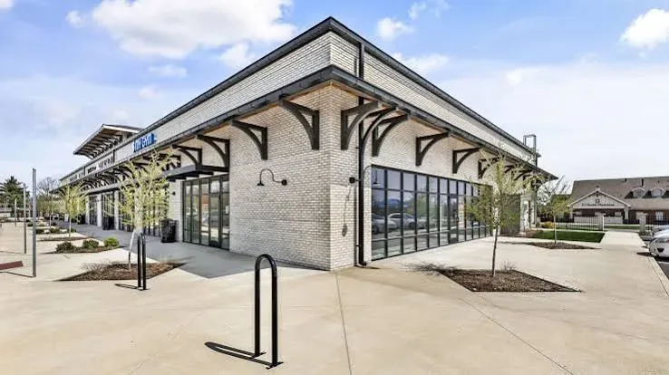A modern retail building with light brick and dark metal-framed windows