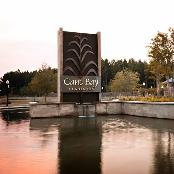 The Cane Bay Plantation entrance monument sign at golden hour, fronted by a pond