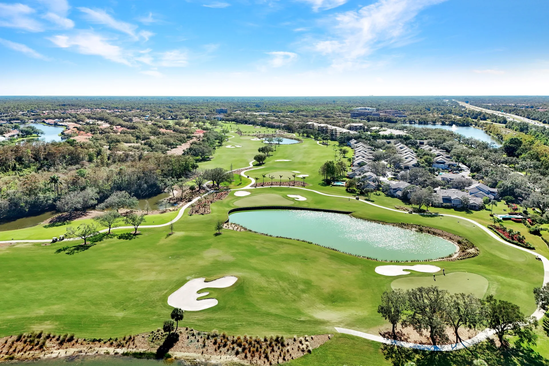 Aerial view of a golf course in The Vineyards with fairways, water hazards, and homes lining the fairway