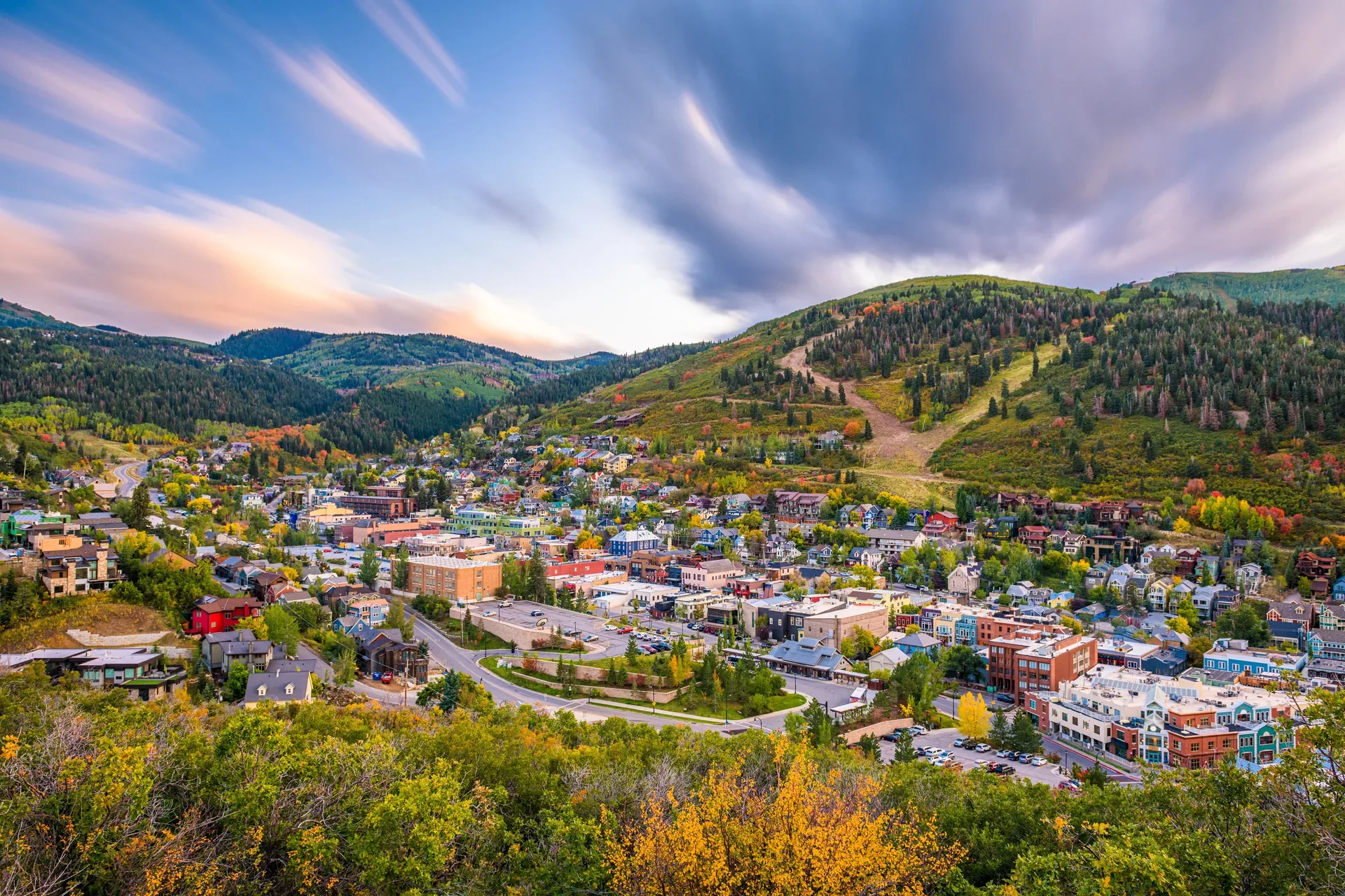 An aerial view of Park City, Utah with fall foliage and mountain town rooftops at golden hour