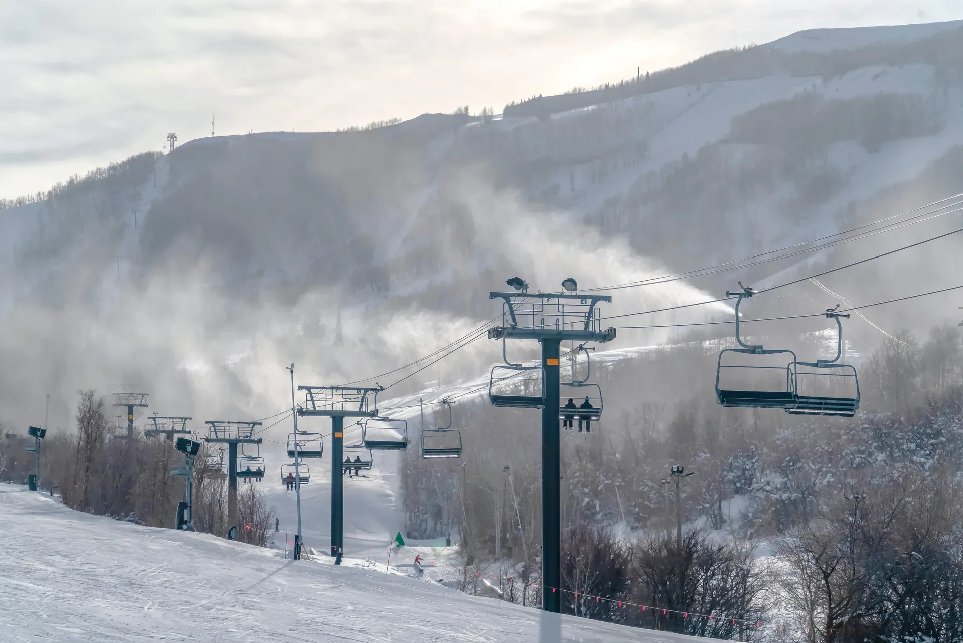 Ski resort slopes with chairlifts and snowmaking equipment under bright daylight