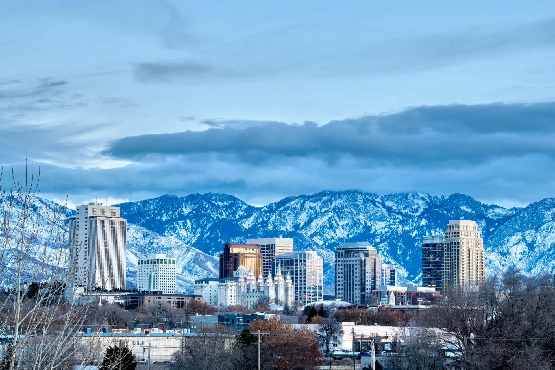 The Salt Lake City skyline under cool winter light with snow-capped mountains behind it