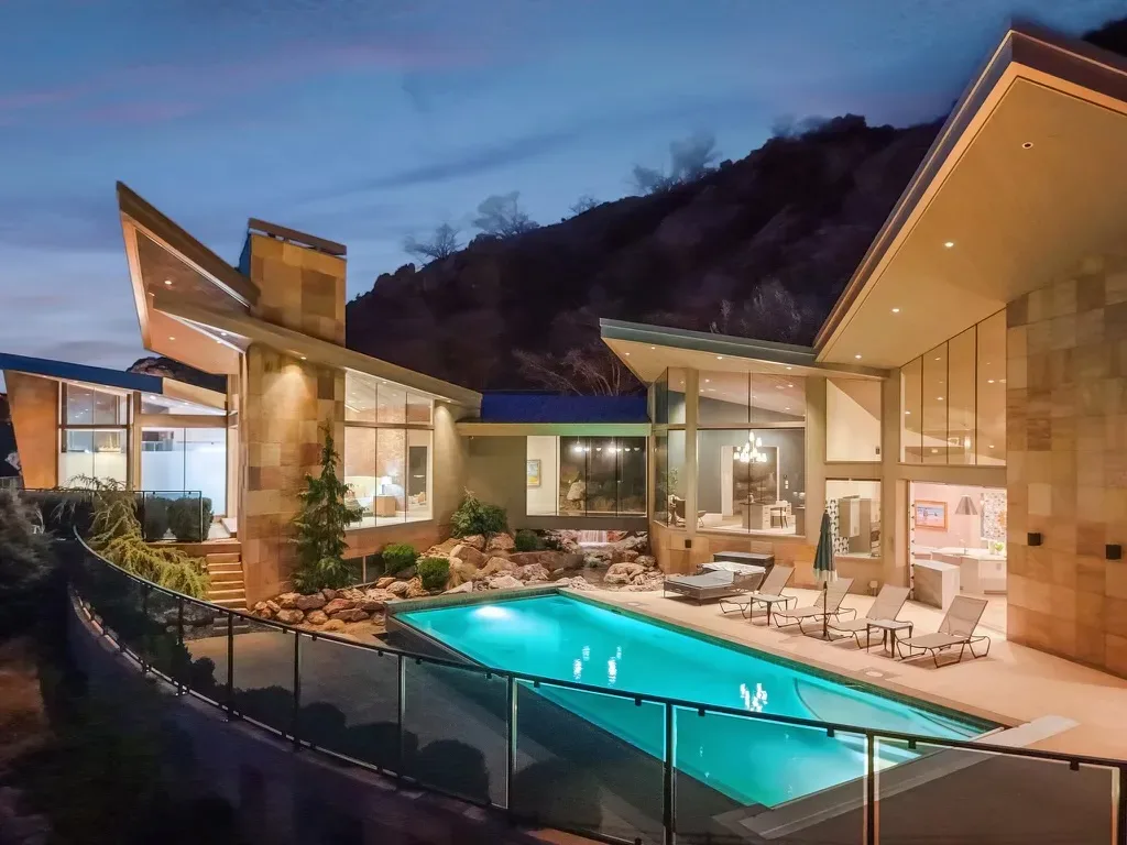 The glowing backyard pool terrace of the Canyon Estate Drive estate at twilight