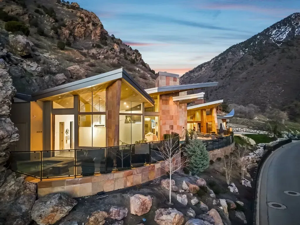Drone view of the luxury estate built into the mountainside with terraced balconies lit at dusk