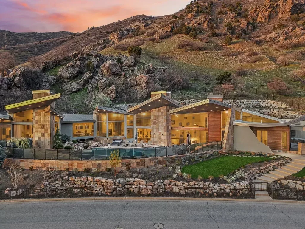 Exterior facade of the Canyon Estate Drive mountain-modern home, glass walls and angled rooflines in twilight
