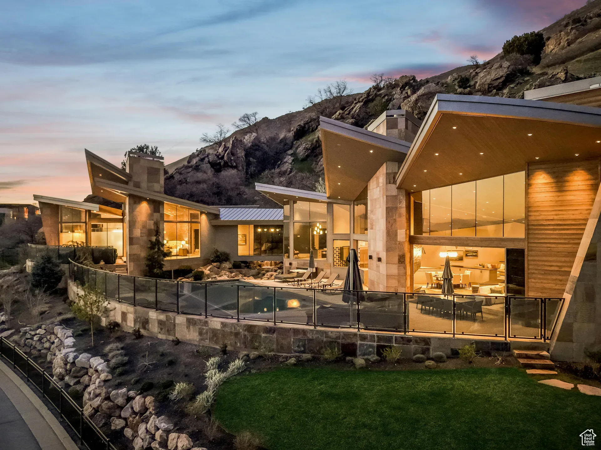 Aerial view of a mountain-modern Deer Valley estate at dusk, angular rooflines and warm glass against the hillside