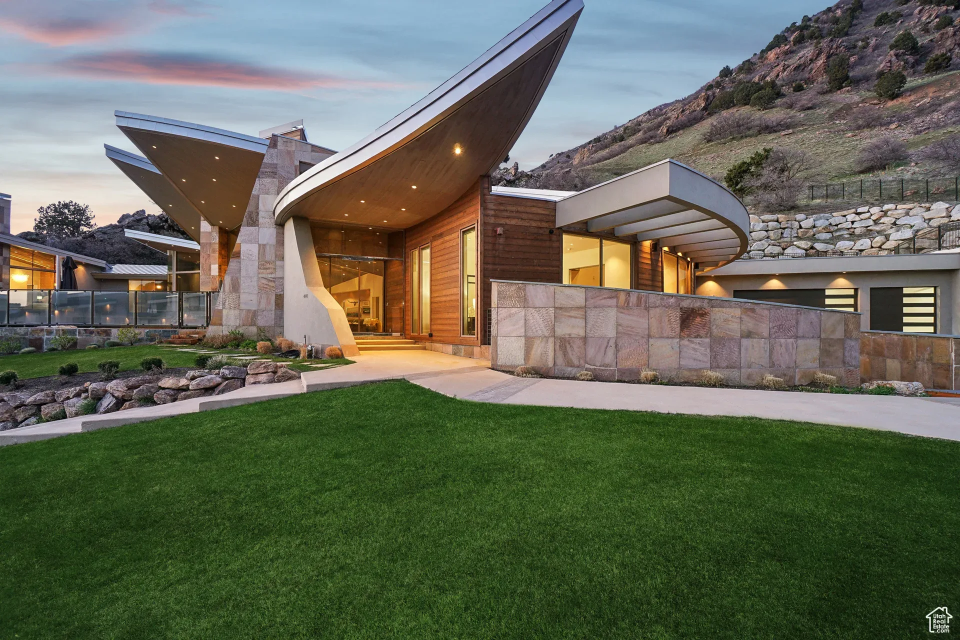 Twilight facade of the Tavaci estate with a sweeping wing-like roofline