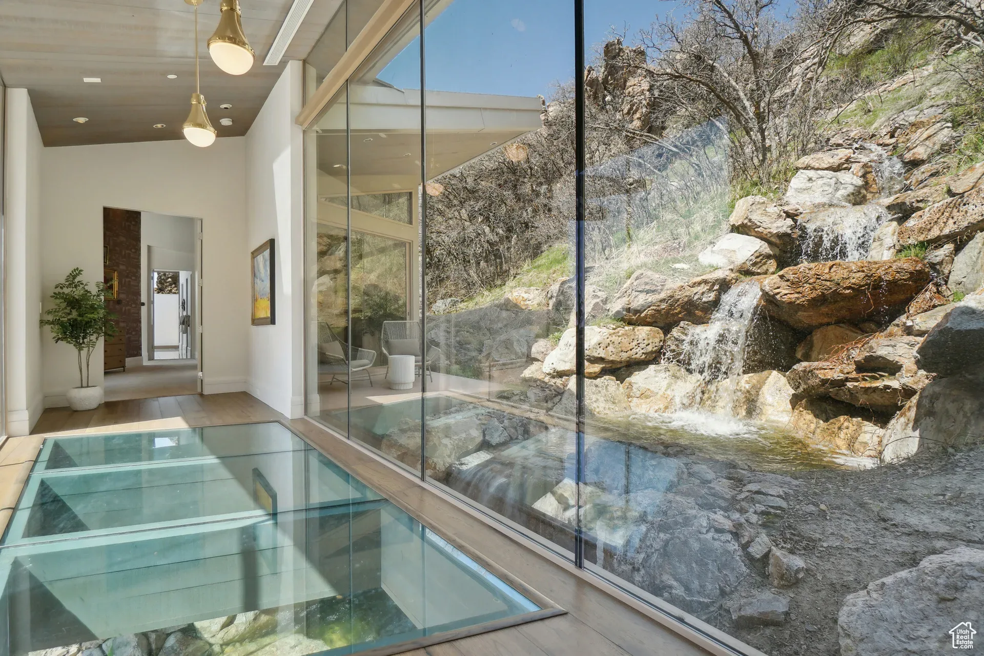 The glass-floor hallway of Tavaci, The Waterfall House, looking out at the tiered rock waterfall