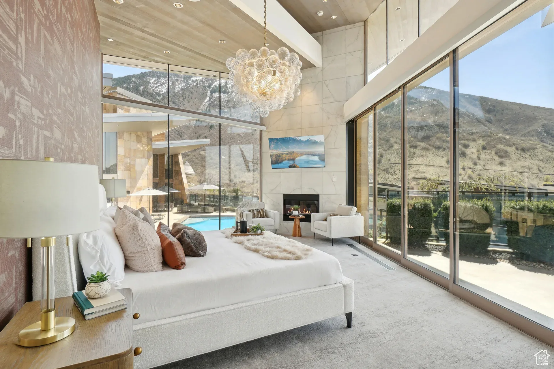 The master bedroom of the Tavaci estate with a fireplace and floor-to-ceiling glass