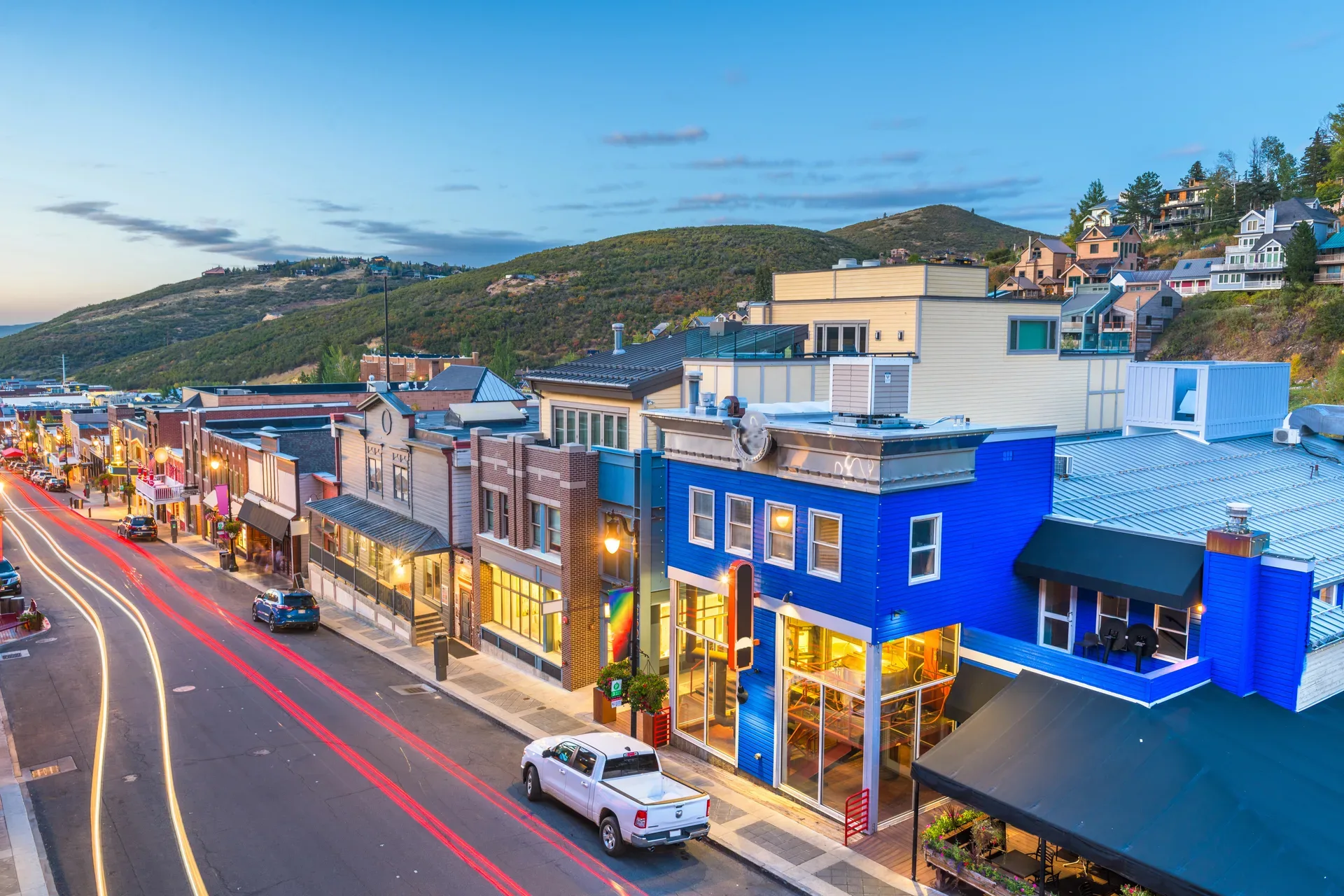 Historic Main Street in Park City at dusk with warm storefront lights and a mountain backdrop