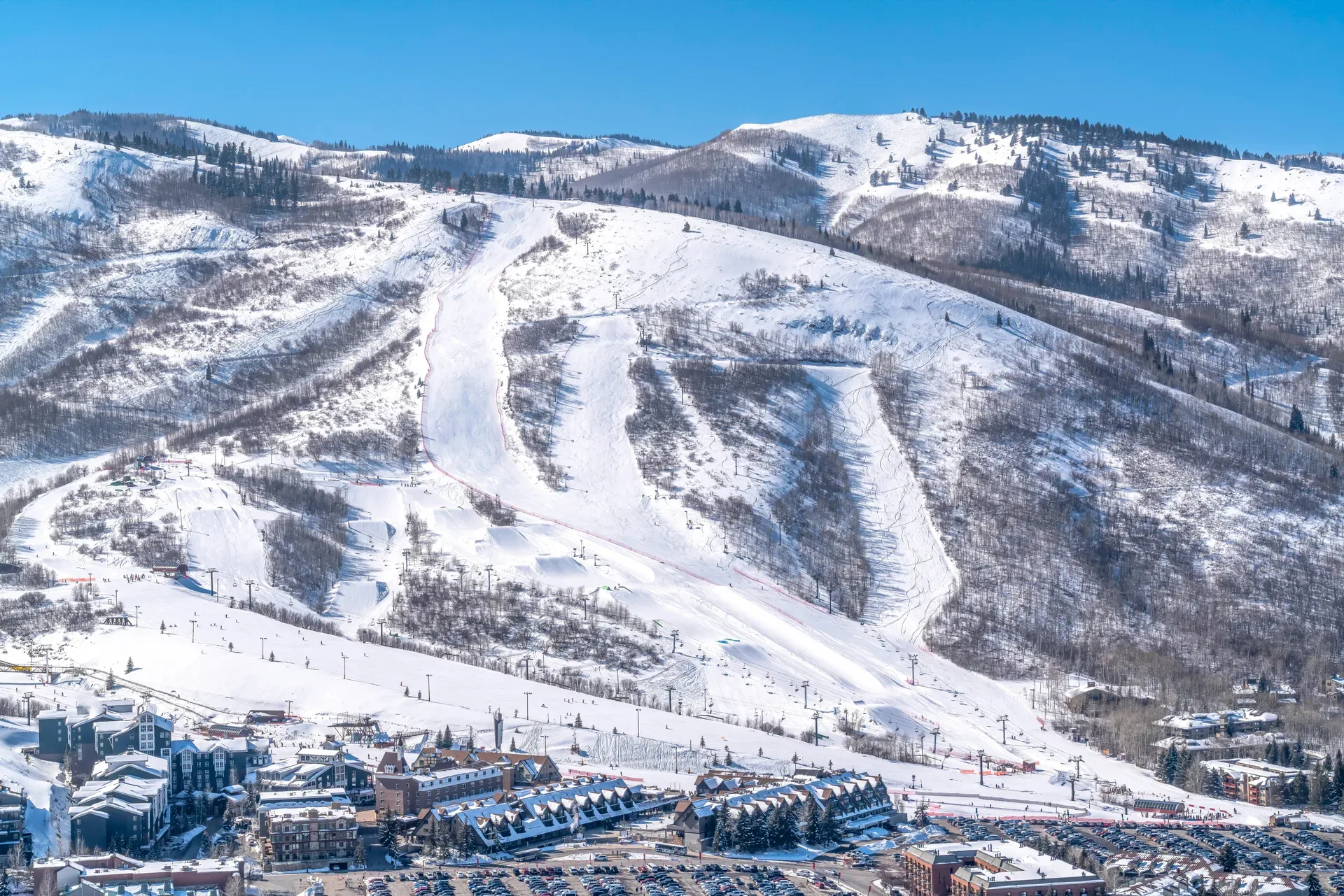 Aerial view of a snow-covered ski mountain and resort village near Park City, Utah under a bright blue sky