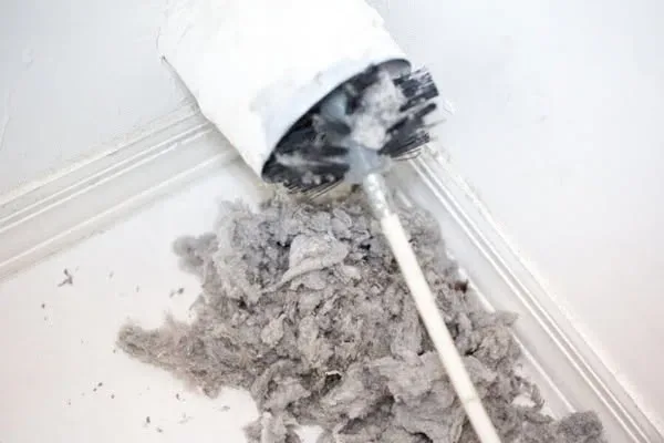Dryer vent cleaning service in San Antonio: a handyman using a duct cleaning tool to remove lint and dust buildup