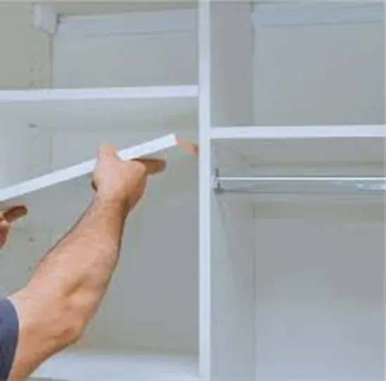 Closet shelving installation in San Antonio: a worker's hands installing white laminate shelving in a closet, turning unused wall space into organized storage