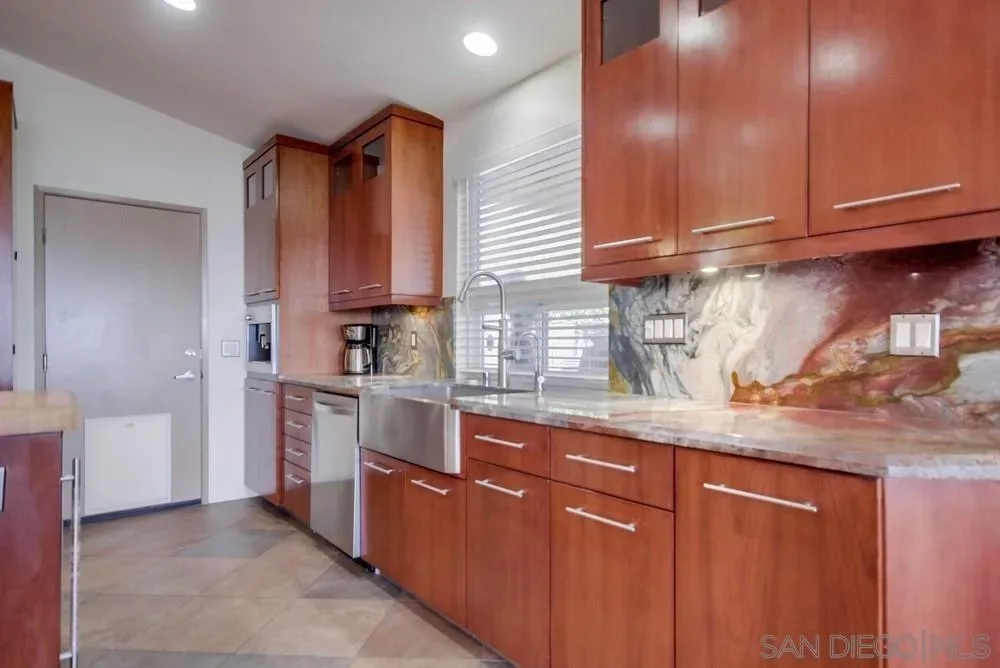 Kitchen with cherry-toned cabinetry and stone backsplash at 2703 Lobelia Road