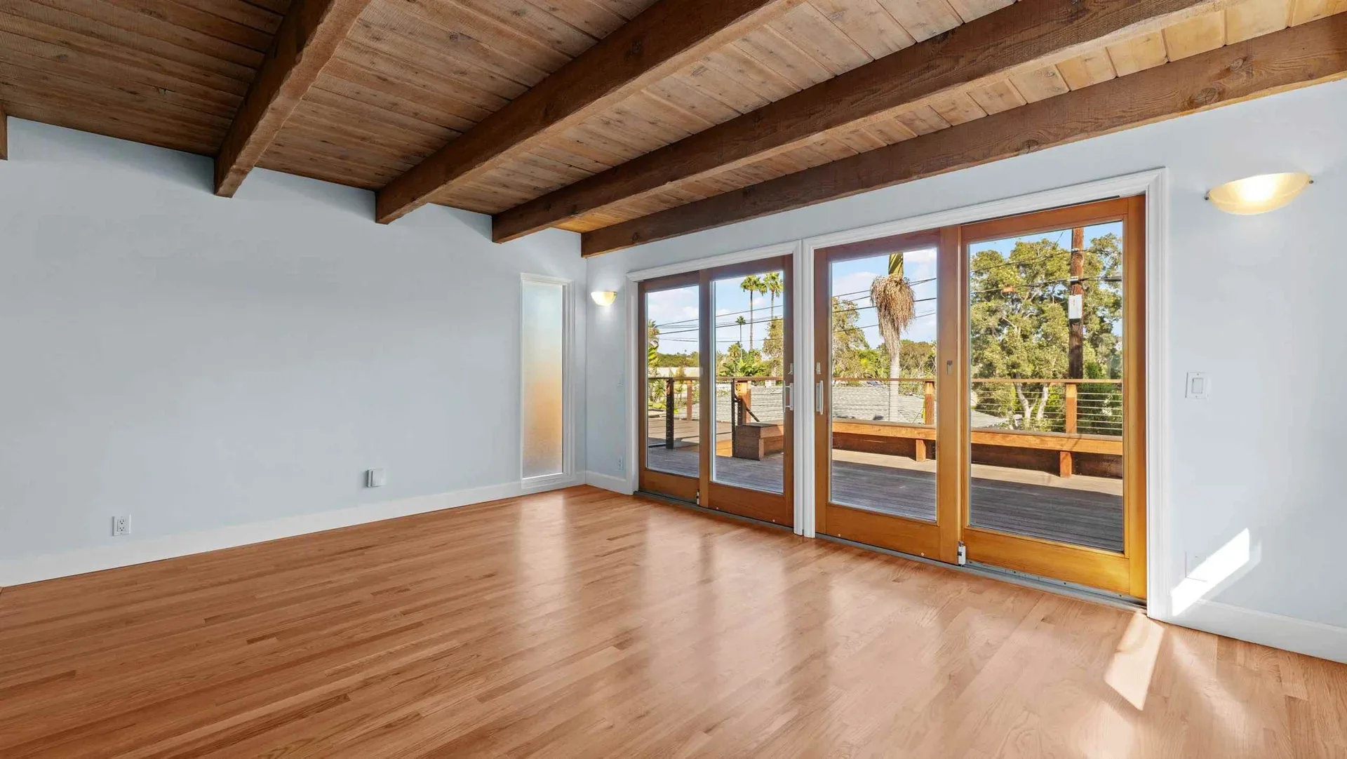 Living room with a vaulted wood-beam ceiling and sliding glass doors to the deck