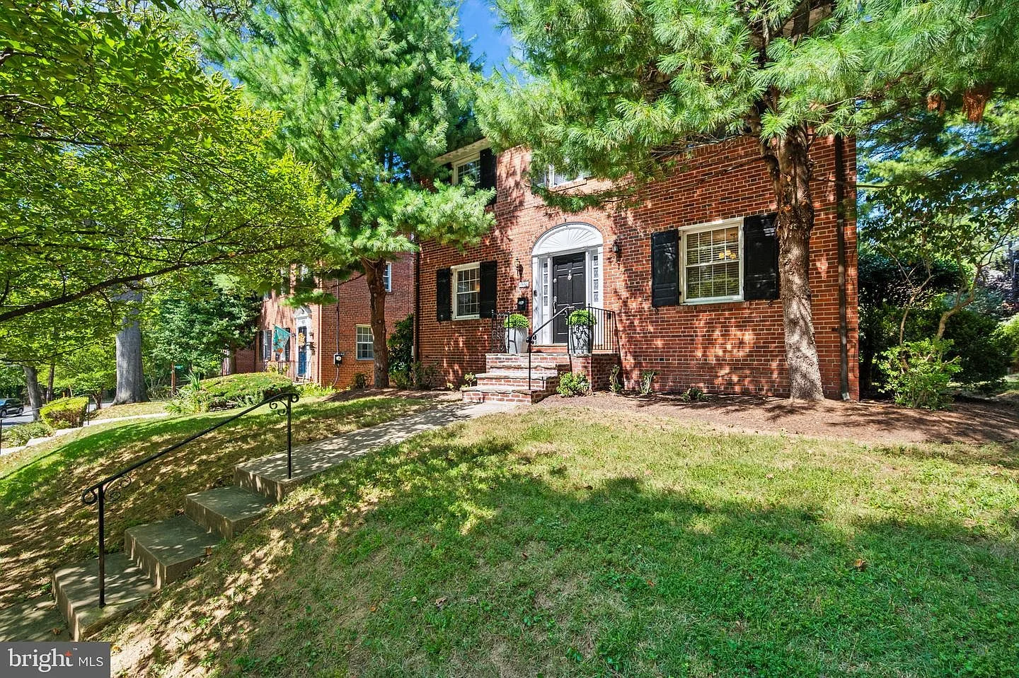 Front facade of the 1942 red brick Colonial at 1667 Primrose Rd NW, with black shutters and mature trees