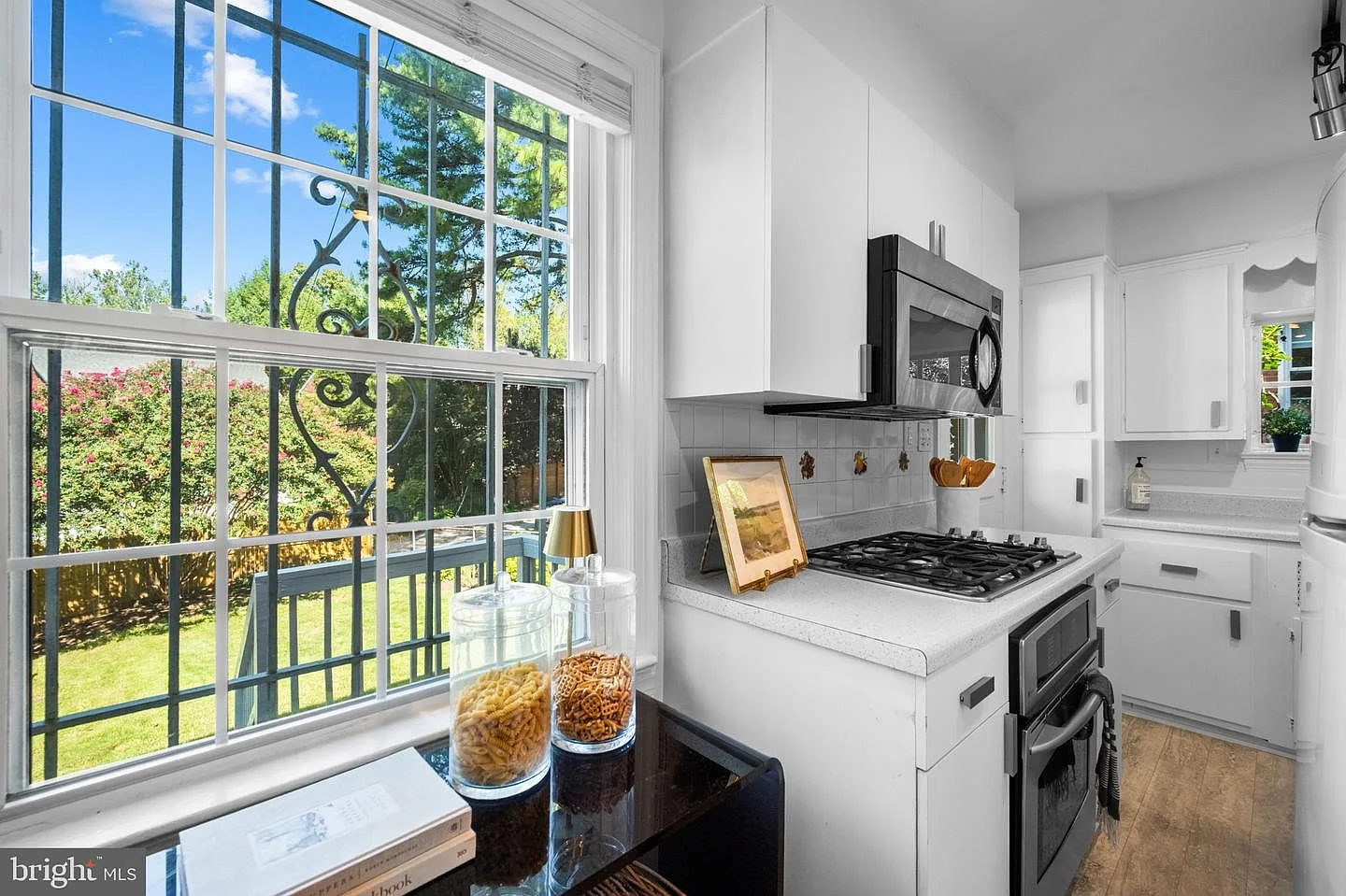 Kitchen window view with white cabinetry and stainless appliances