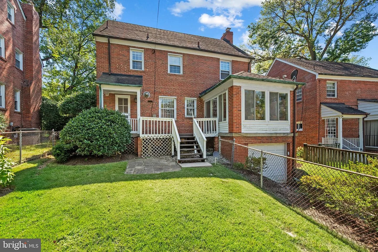 Rear facade with wooden deck, stairs, and grassy yard