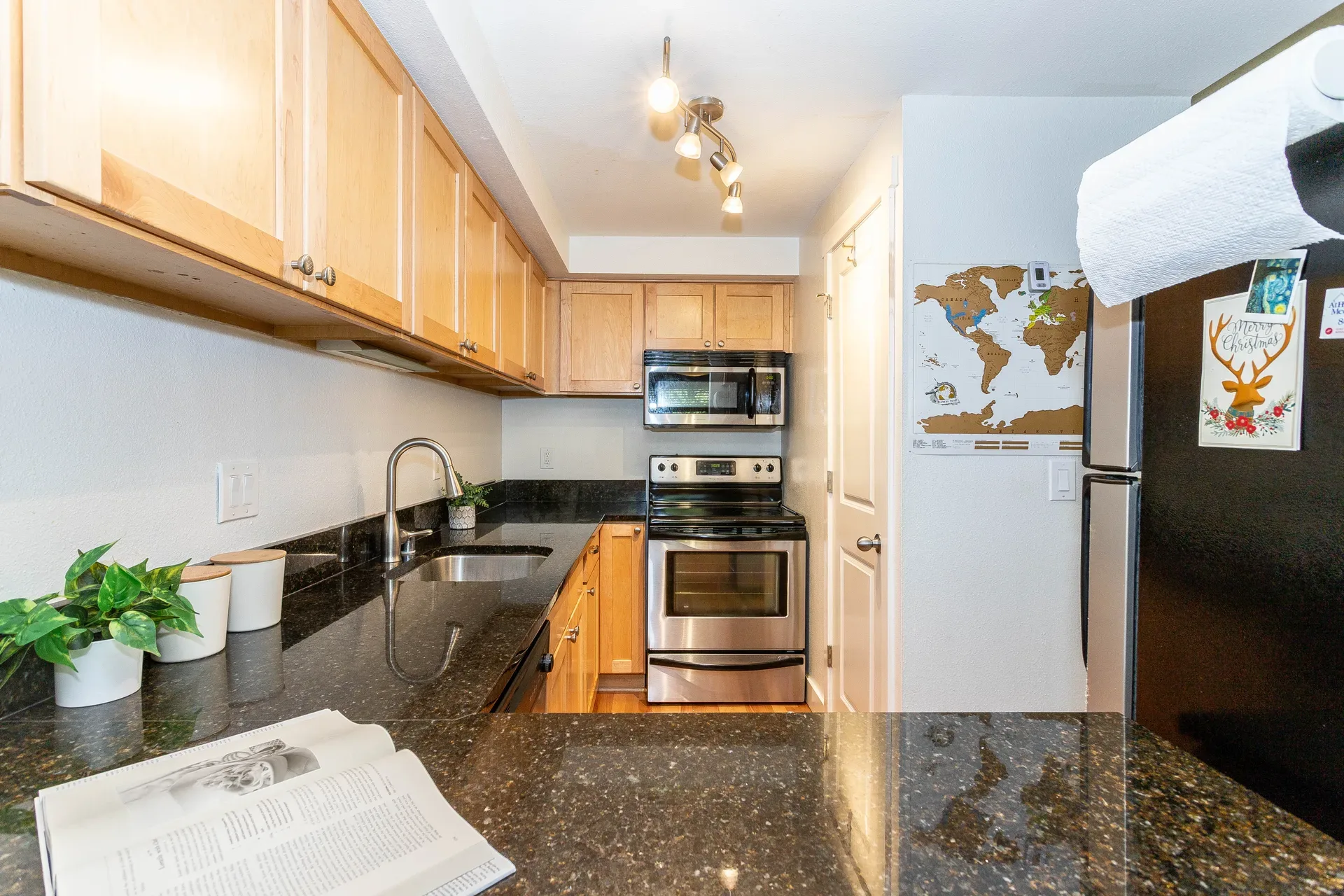 The kitchen of G301 at Horizon Village with stainless steel appliances, granite countertops, and maple shaker cabinetry