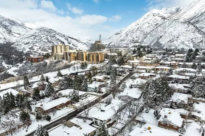 A winter drone view of the east bench neighborhoods at the foot of the snow-covered Wasatch Range