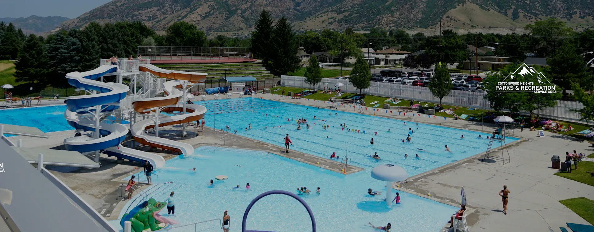 The Cottonwood Heights community pool and recreation center with its twin water slides and lap lanes under a sunny sky