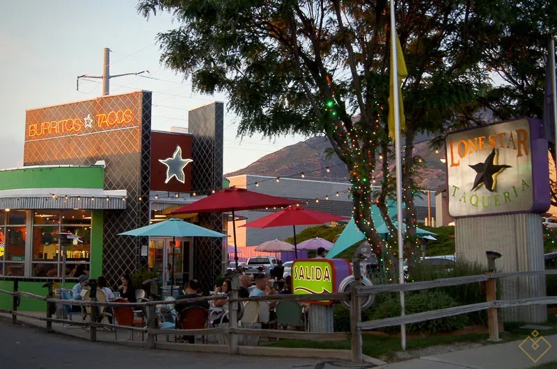 A colorful local taqueria with a patio and string lights glowing at dusk