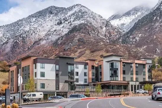 A mountain-view hotel facade with snow-capped peaks rising behind it