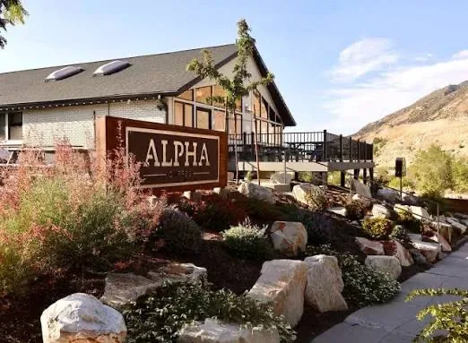 A lodge-style mountain exterior with a broad wooden deck and boulder landscaping