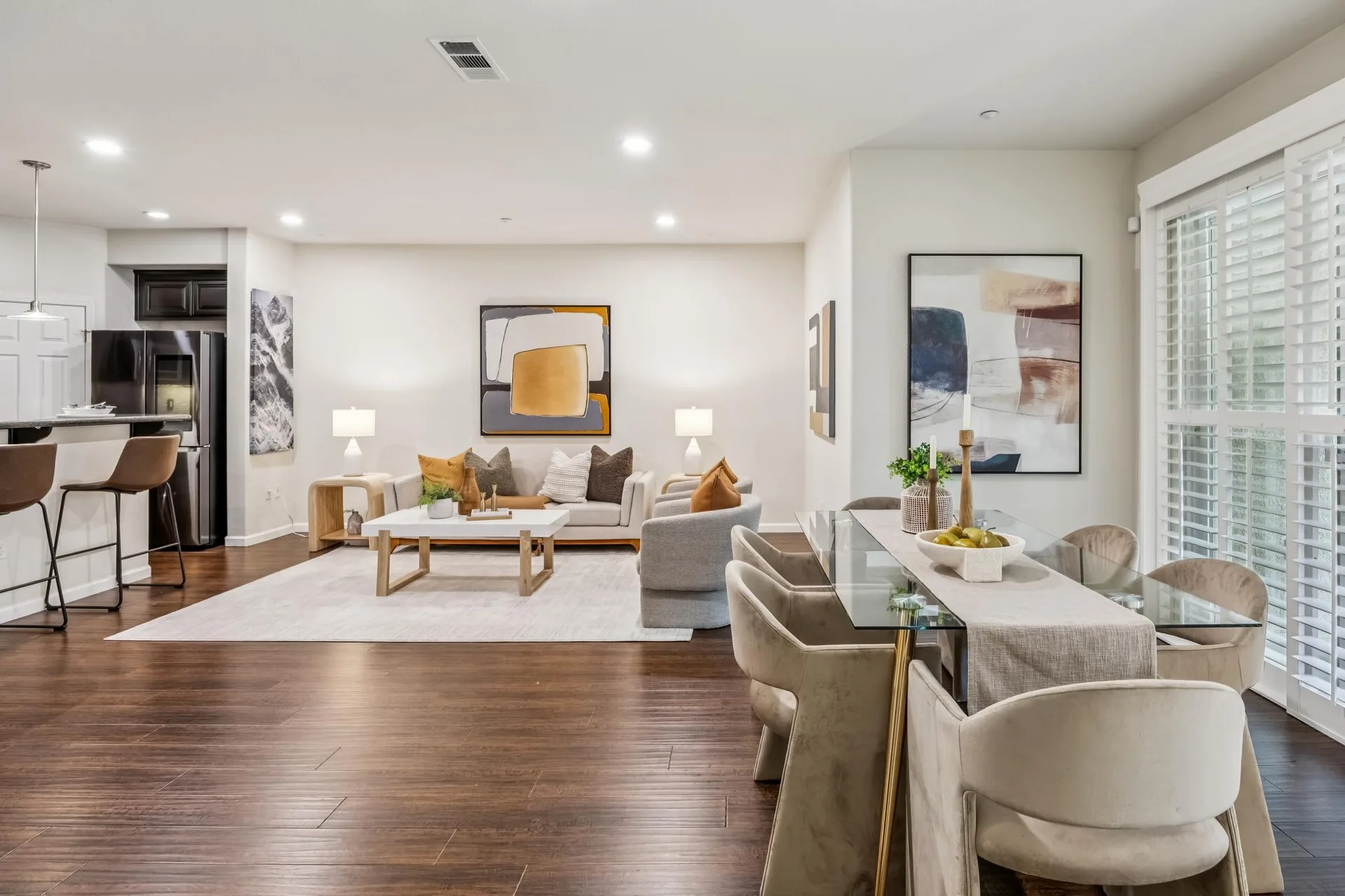 Open-concept living and dining room with neutral walls and abstract art