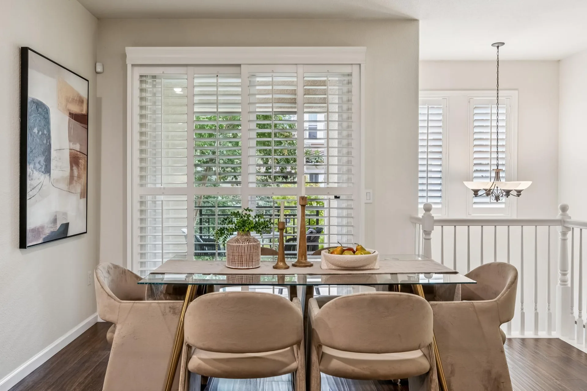 Dining area with glass-top table, plantation shutters and natural daylight