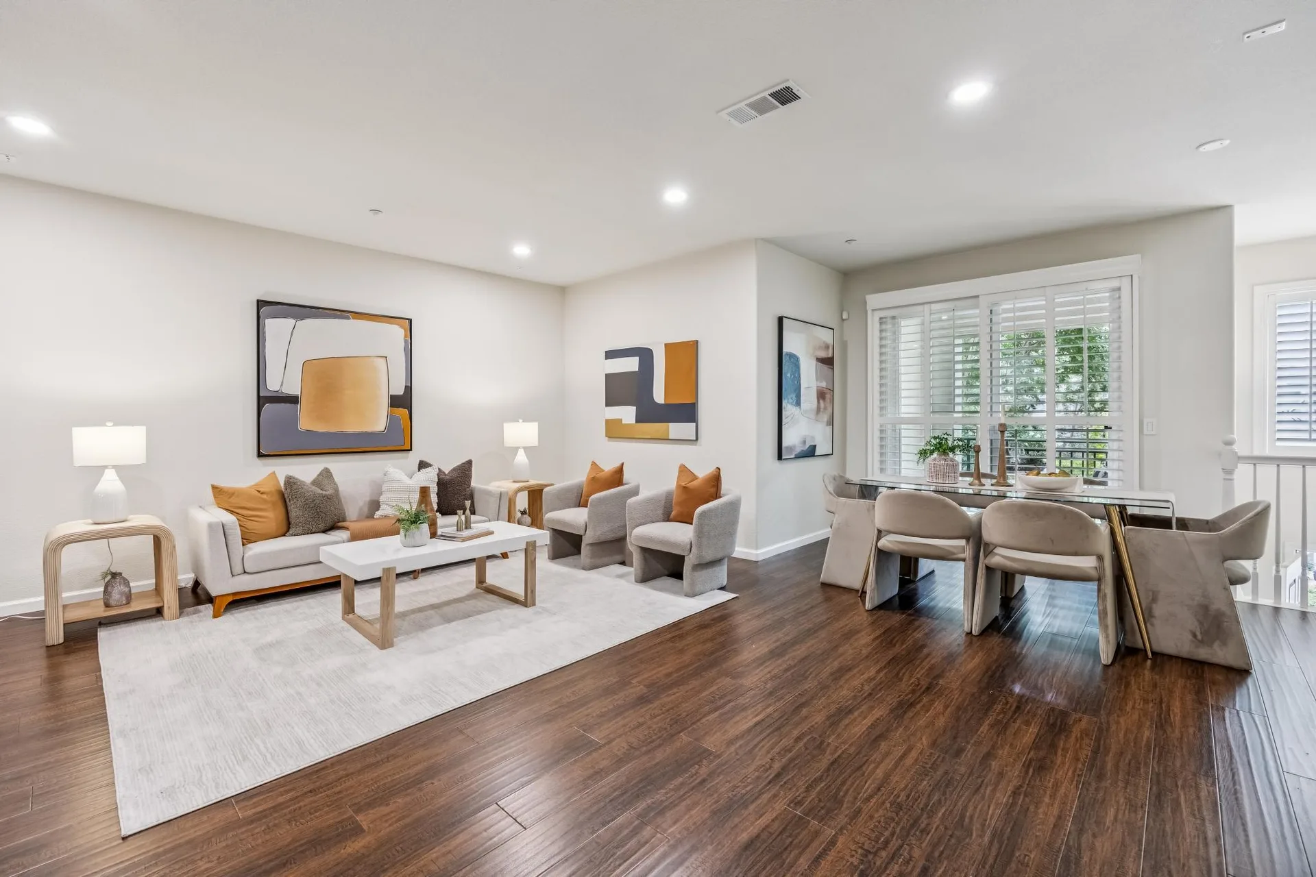 Wide open-concept living and dining area with dark wood floors, recessed lighting and white shutters