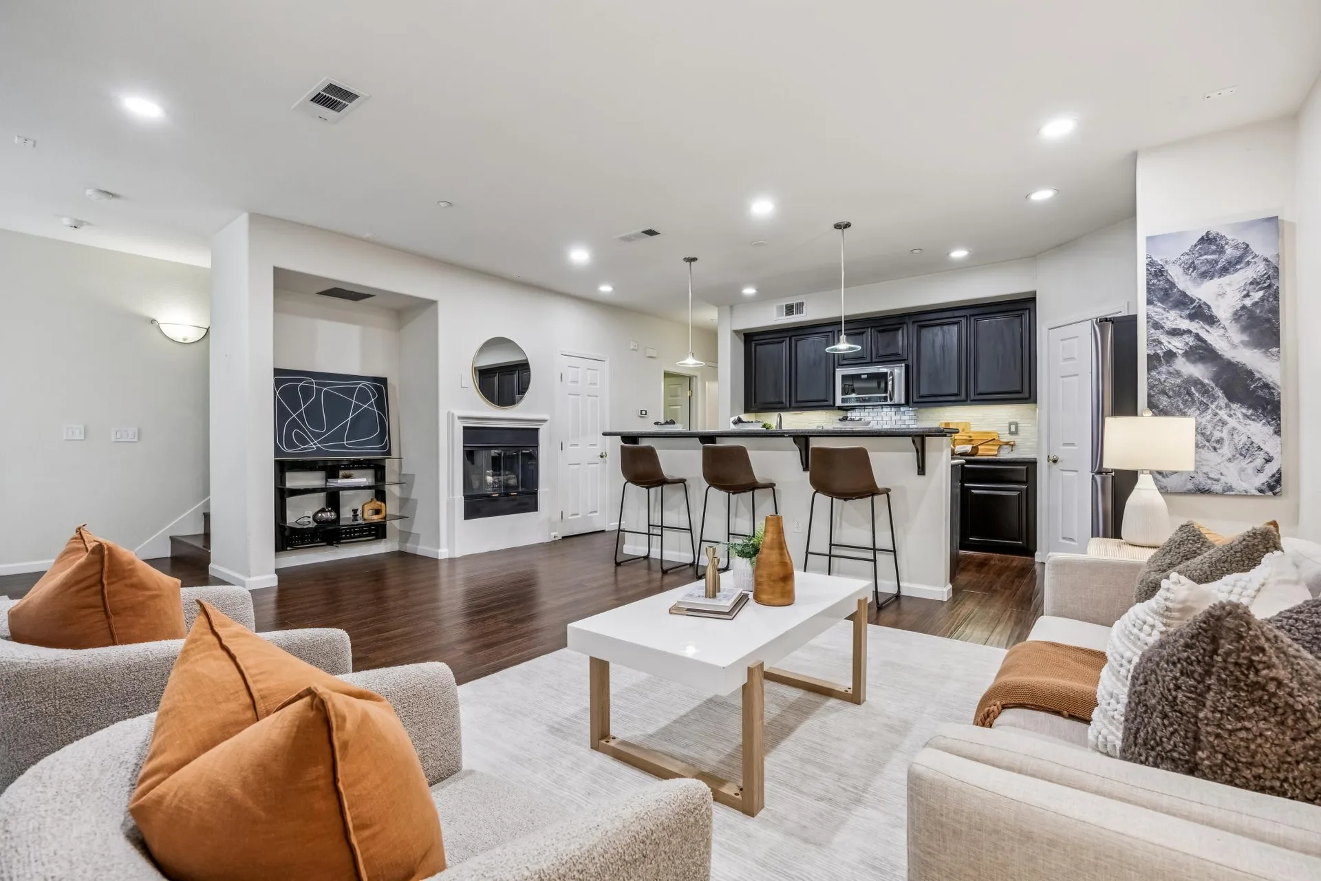 Open living room and kitchen with fireplace, bar stools and pendant lights