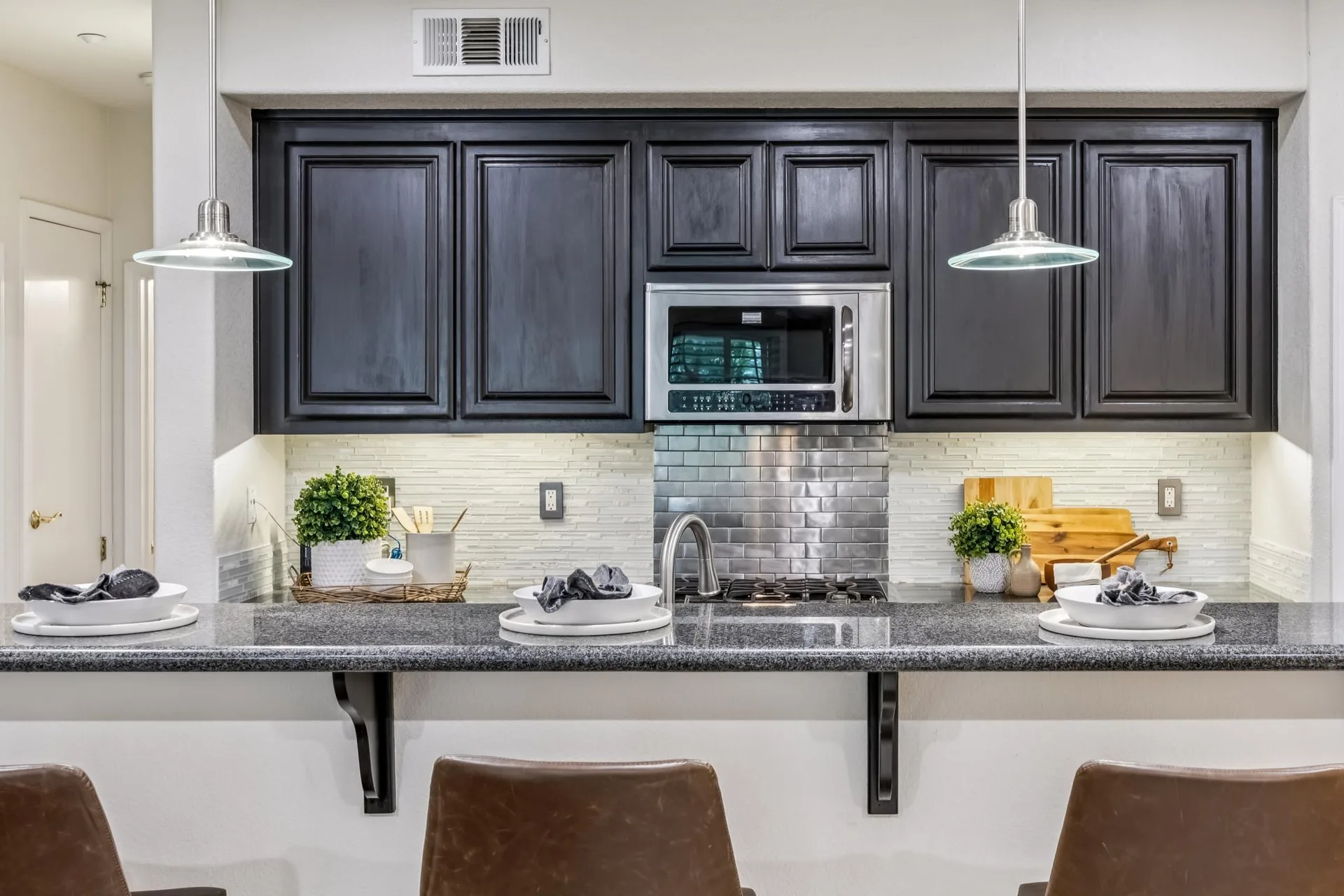 Kitchen breakfast bar with metallic subway tile backsplash and granite counters
