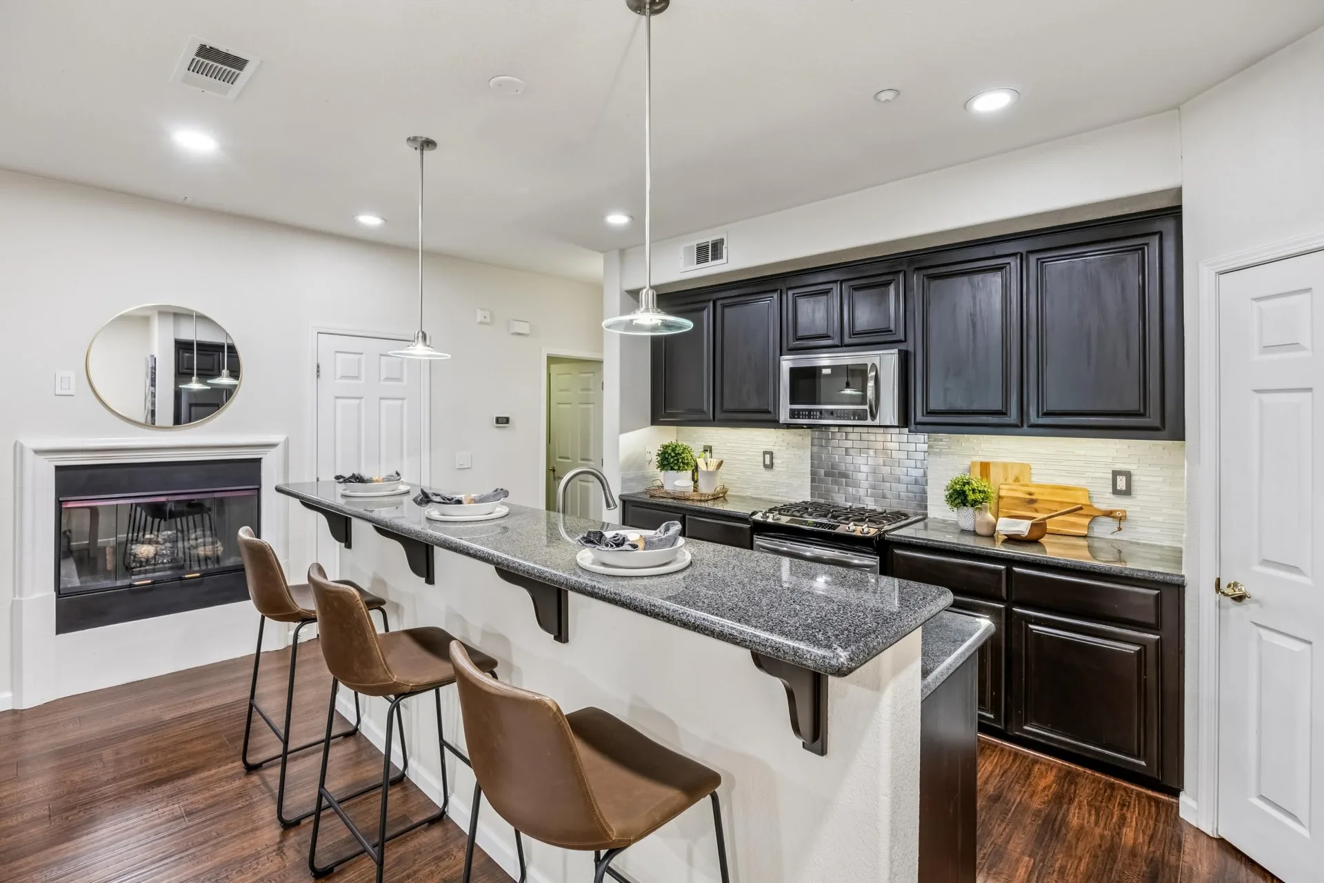 Kitchen with breakfast bar, fireplace beyond and dark wood cabinetry