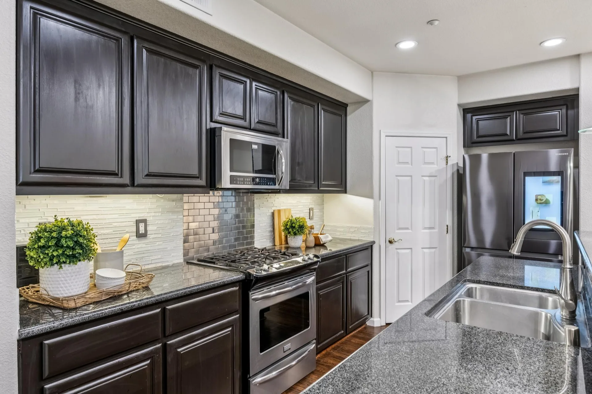 Kitchen with dark espresso cabinets, stainless appliances and stacked stone backsplash