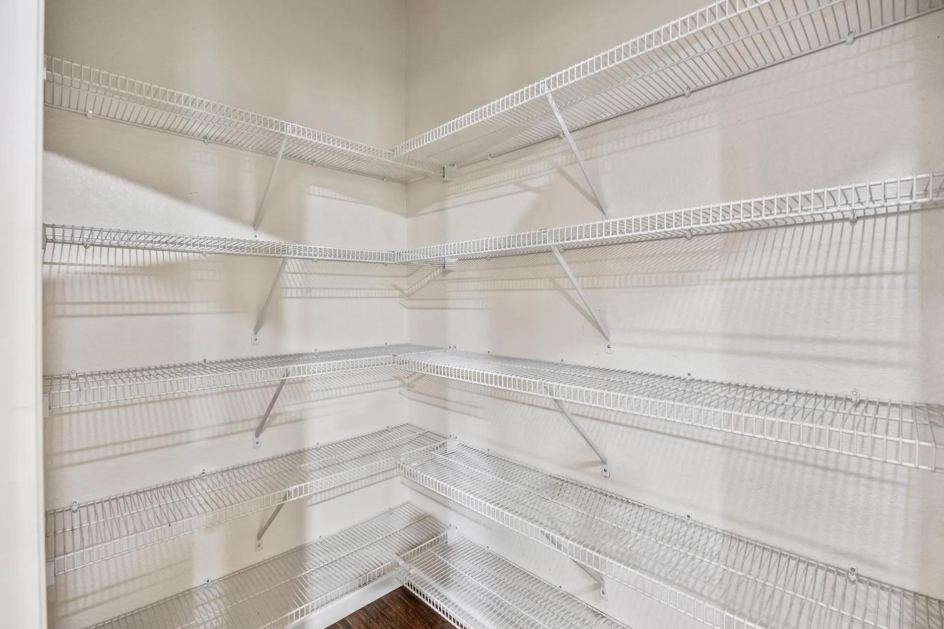 Walk-in pantry with white wire shelving on three walls