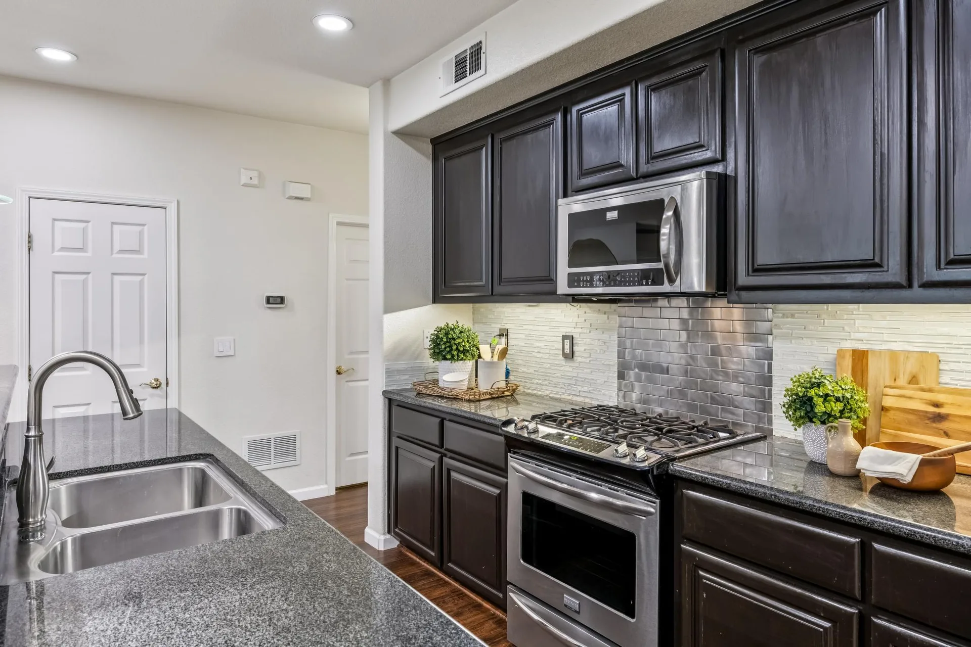 Kitchen counter with dark cabinetry, granite counters and tile backsplash