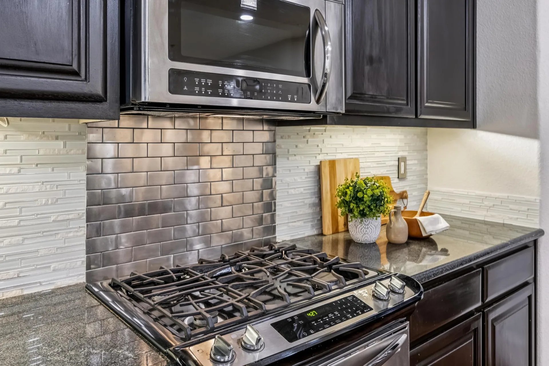 Stainless gas range, microwave and subway-tile backsplash in the kitchen
