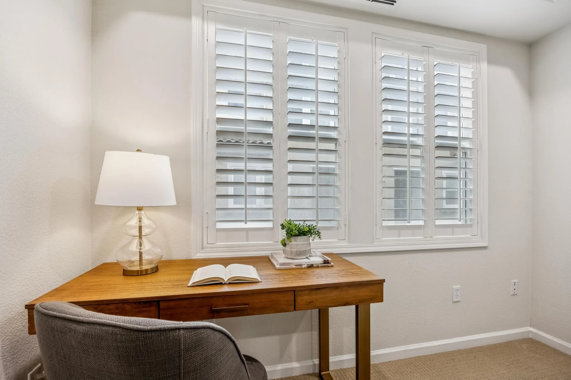 Second bedroom arranged as a home office with plantation shutters