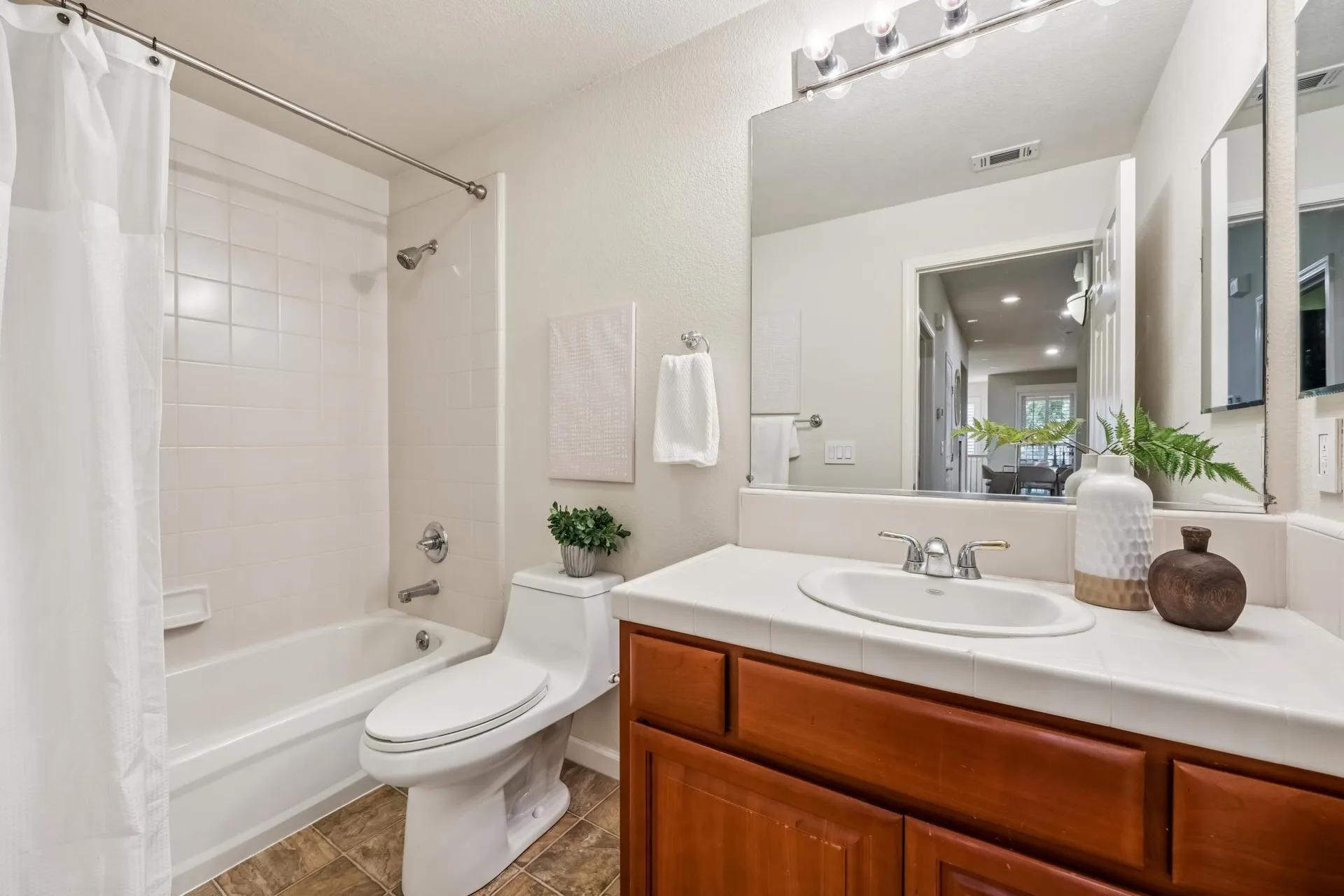 Bathroom with tiled counter, wooden cabinetry and tub-shower combo